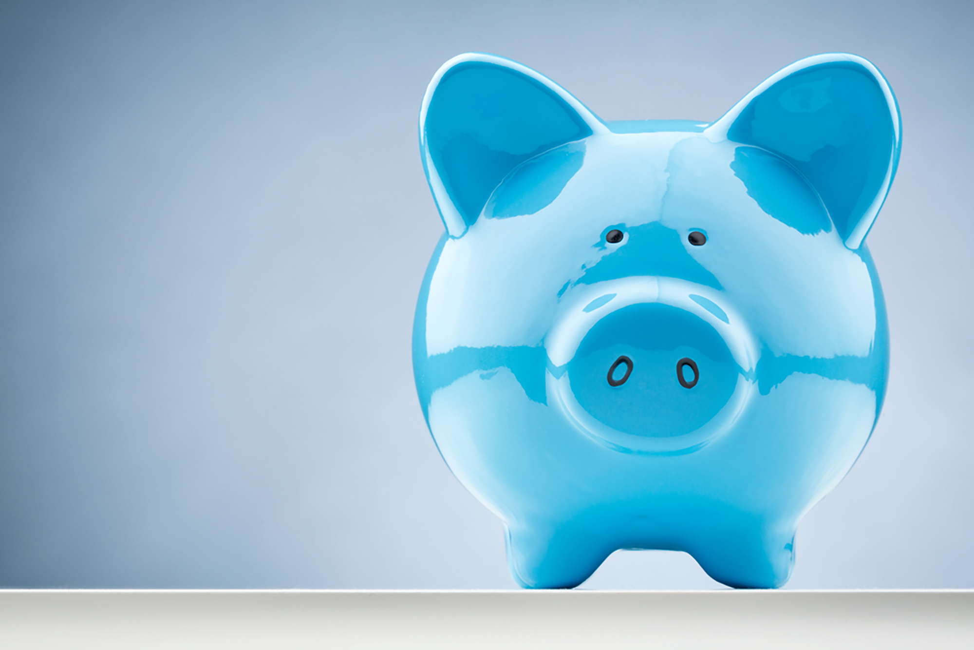 Blue ceramic piggy bank on a light background.