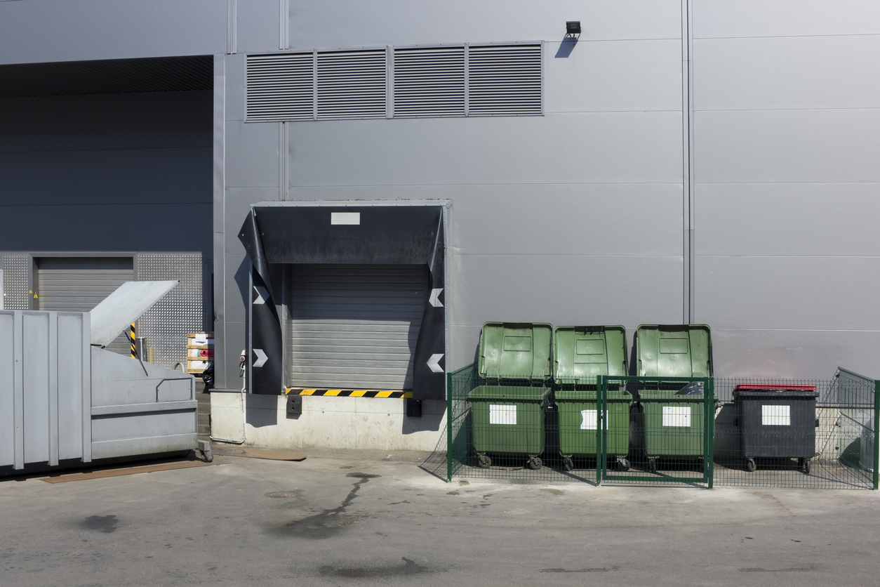 Dumpster diving behind grocery store highlighting food waste and discarded edible food