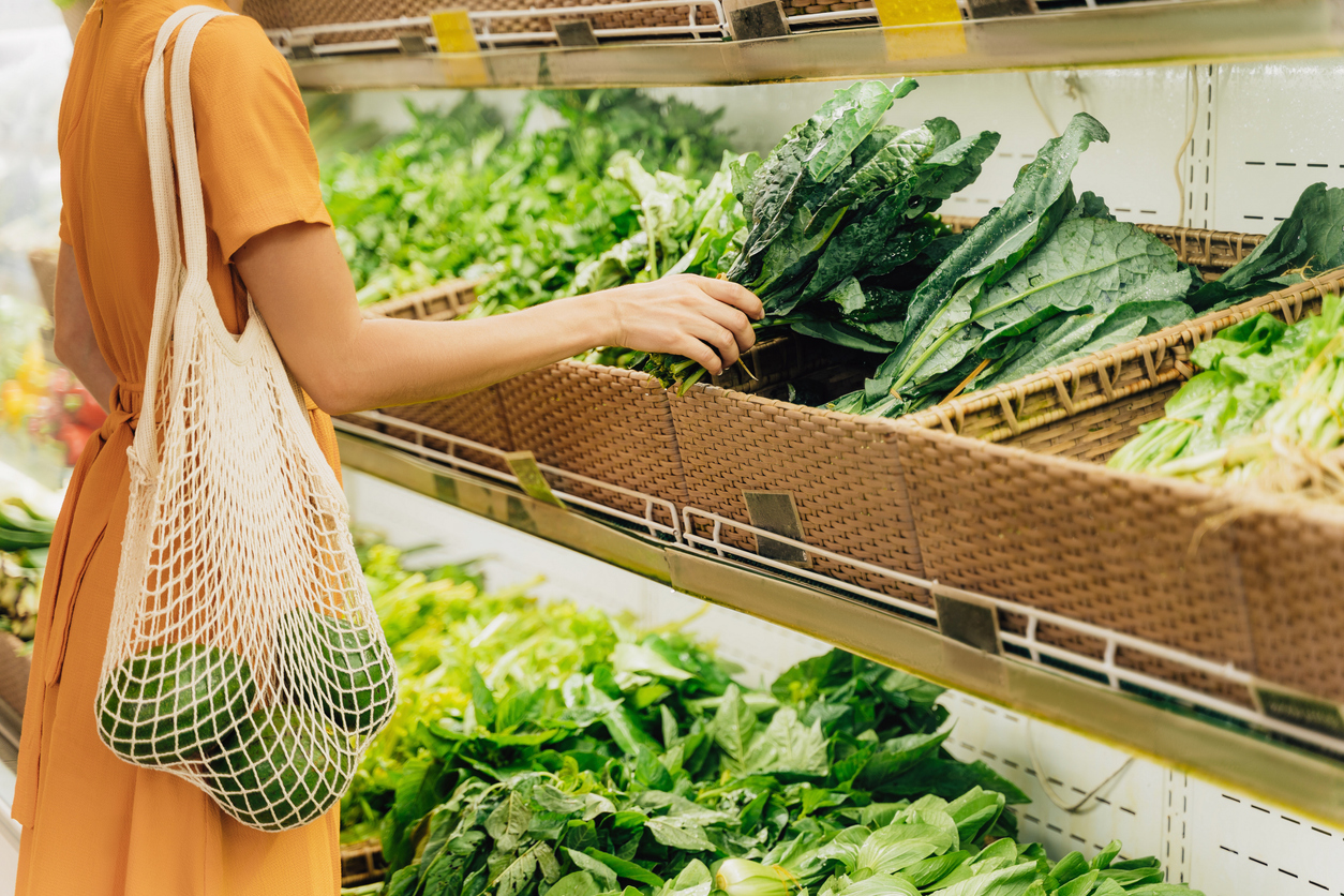 Woman choosing fresh leafy vegetables in supermarket as concept for reducing food waste and sustainable food choices