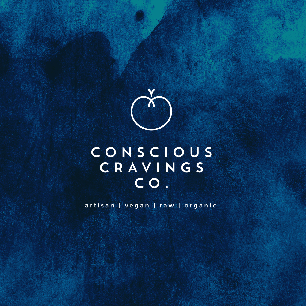 Conscious Cravings Co white logo with tagline (artisan - vegan - raw - organic) on a custom textured blue background