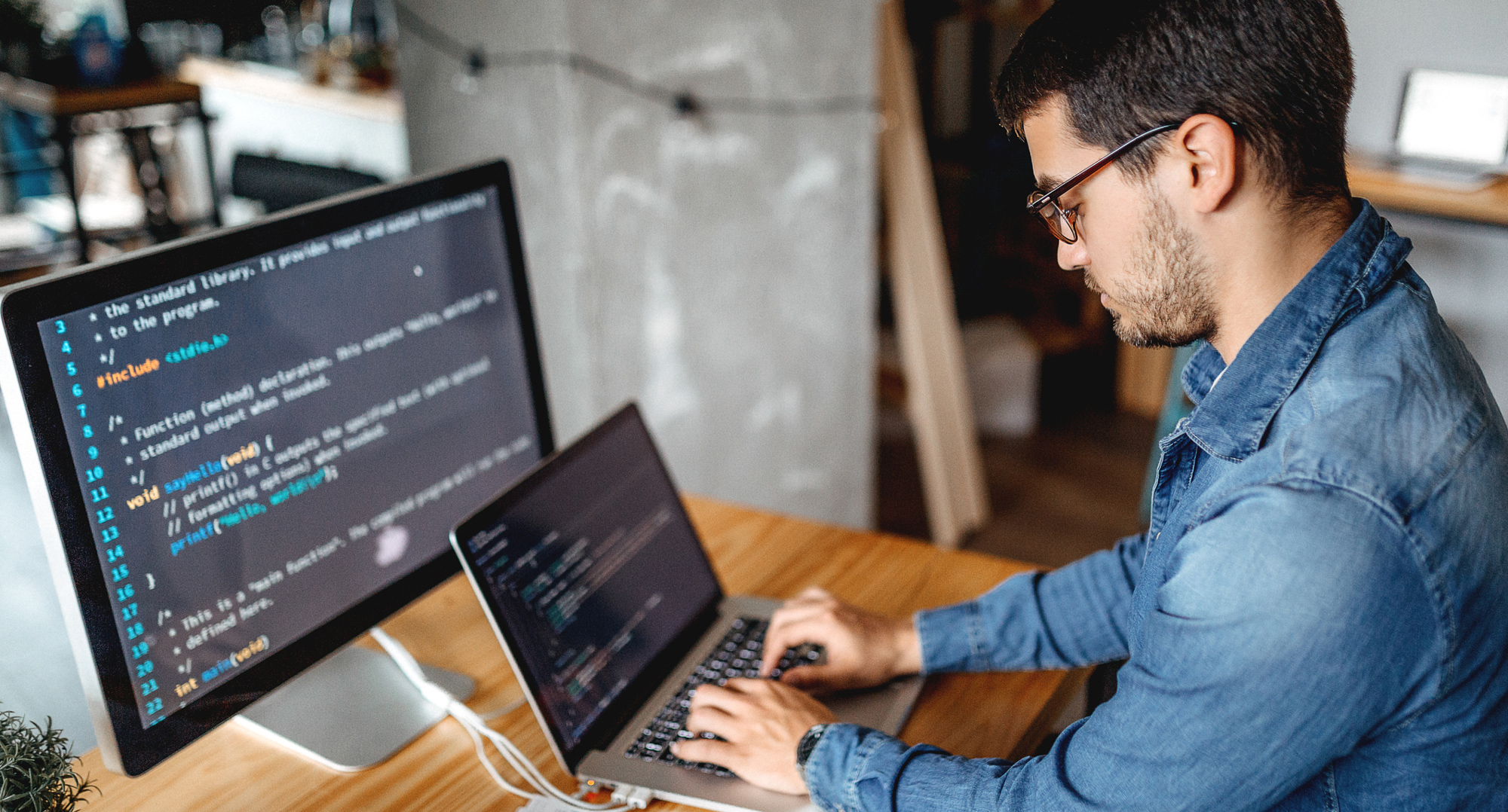 Image of man sitting at desk typing on laptop - iStock image