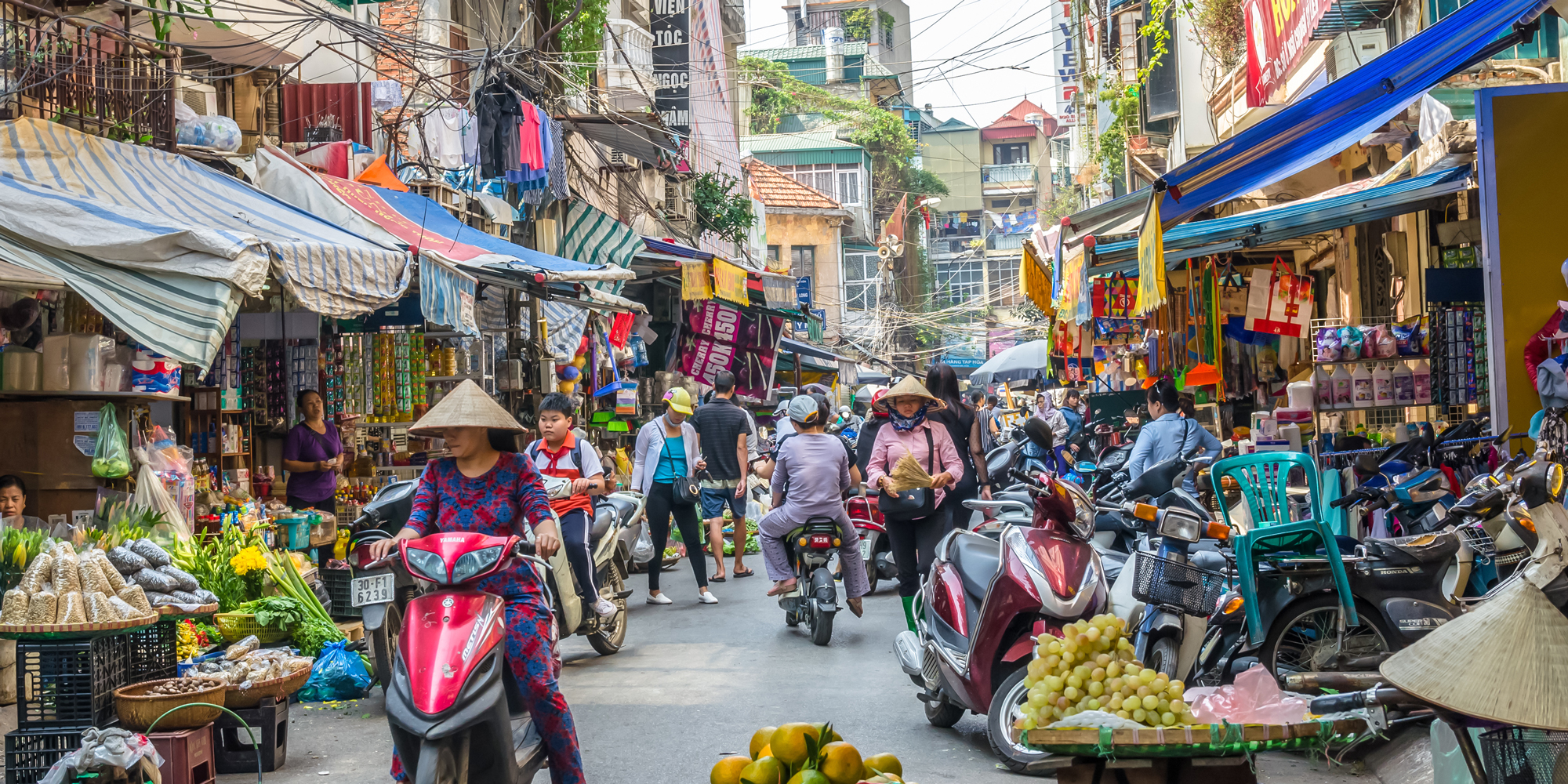 Busy local daily life of the morning street market in Hanoi, Vietnam. A busy crowd of sellers and buyers in the market.