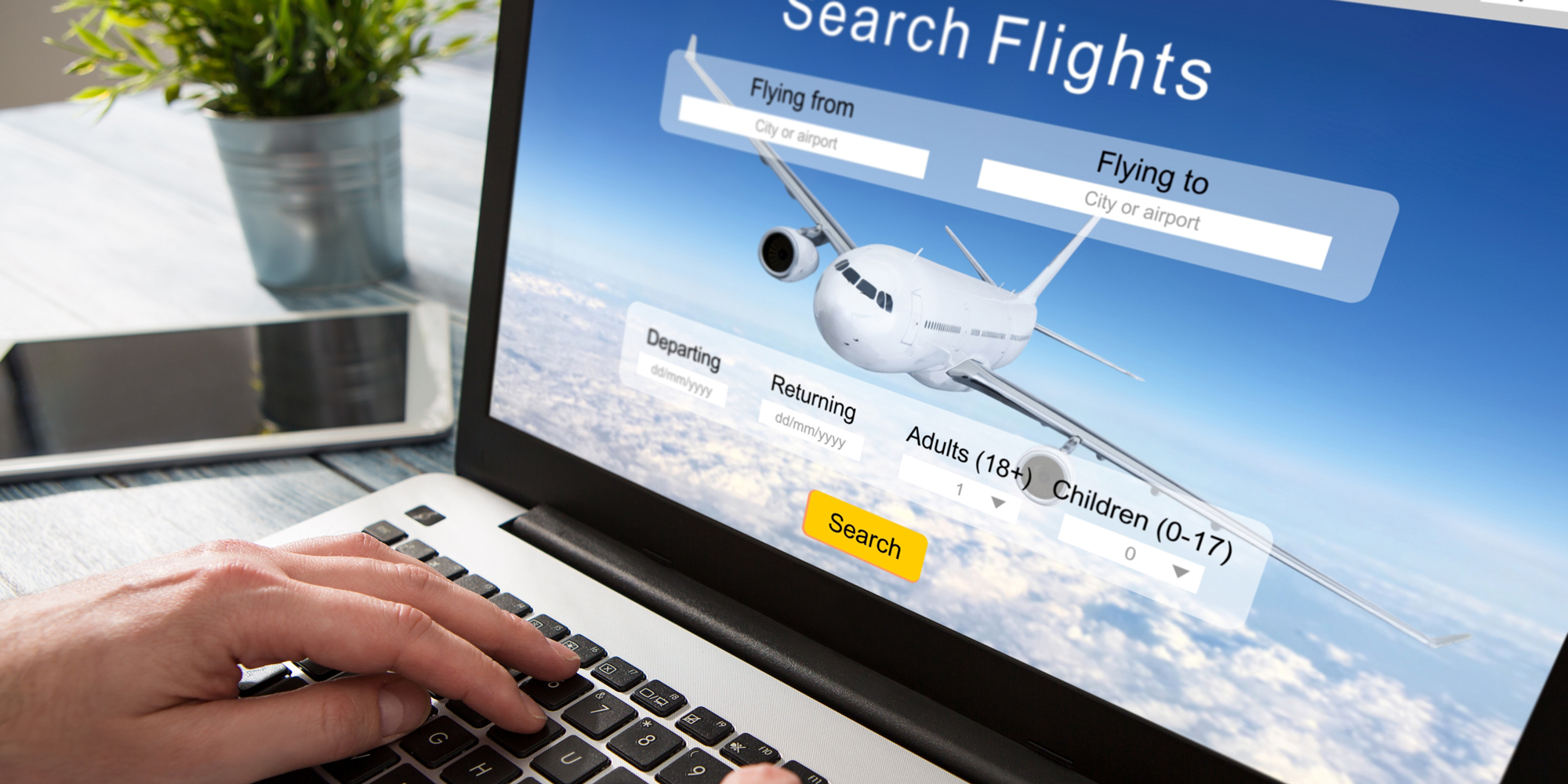 Cropped image of a would-be traveller booking a flight online on a laptop.