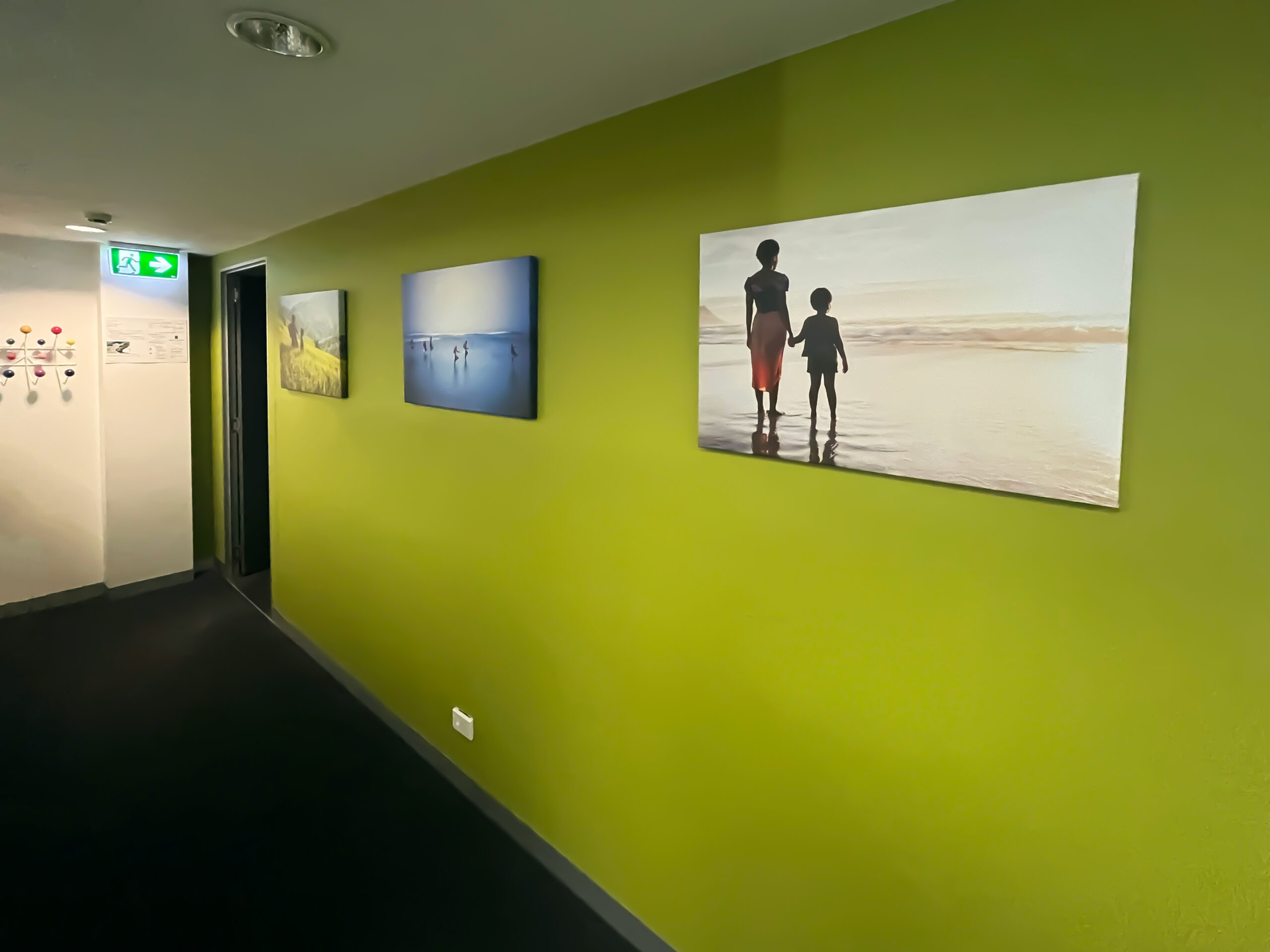 Large gallery-wrapped canvas photo prints, designed and printed by EDCo., decorating the green feature wall at MDGH’s office.