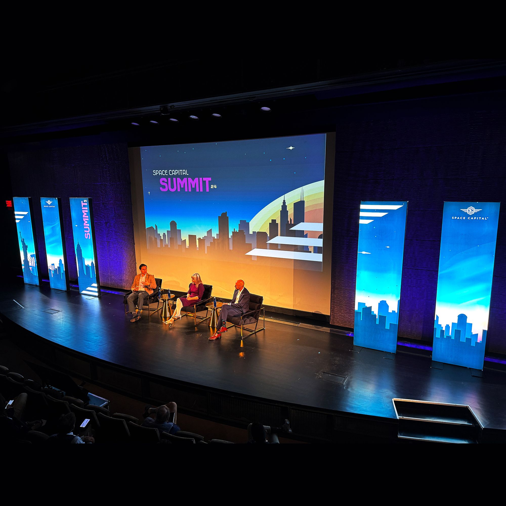 Stage setup for the Space Capital Summit 2024, featuring futuristic designs and cityscape visuals.