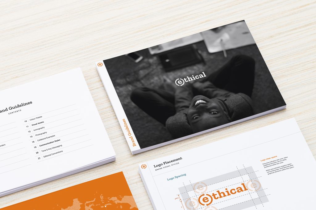 Brand guidelines mockup for (e)thical showing cover, contents page, and logo placement design, displayed in full colour on a light wooden background.