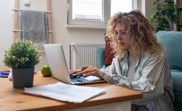 Stressed woman looking at computer screen in a cluttered workspace, representing the overwhelm of digital clutter.