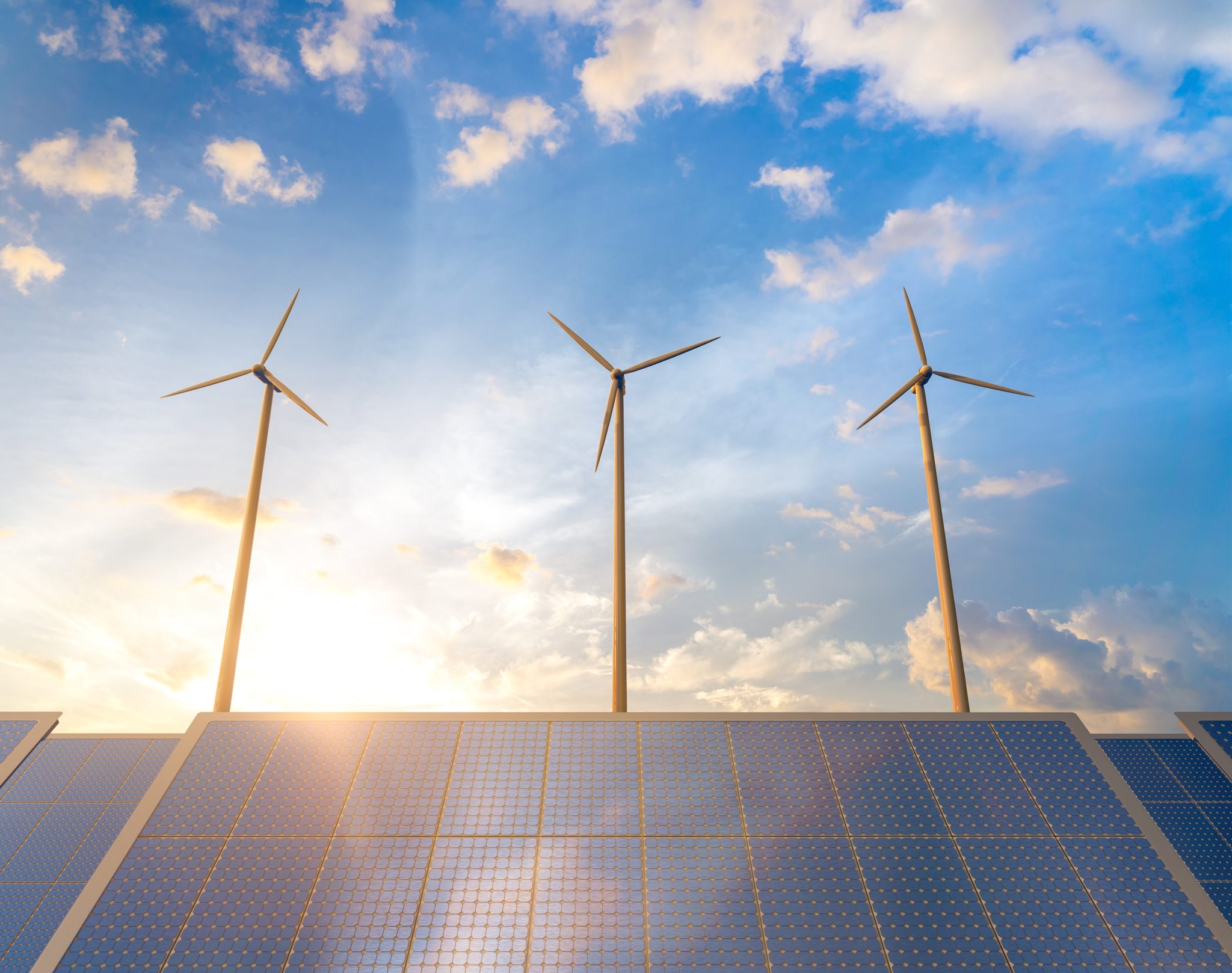 Solar panels and wind turbines at sunset, symbolising the shift toward sustainable energy in tech infrastructure.